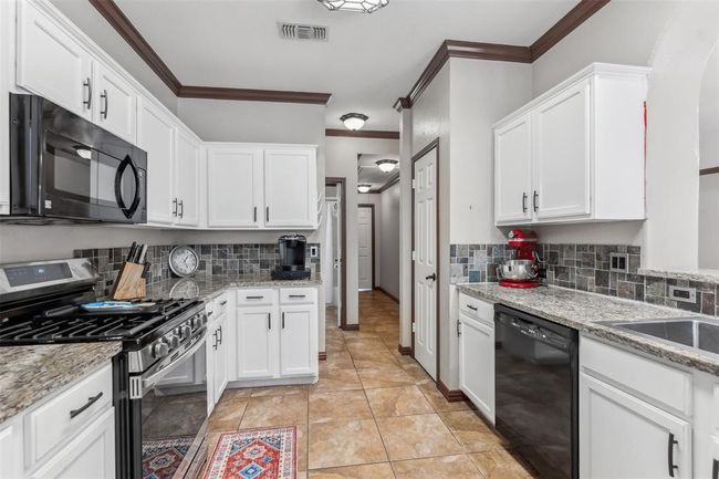 Kitchen featuring visible vents, white cabinets, and black appliances | Image 11