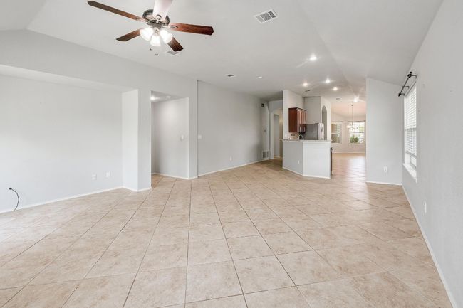 Unfurnished living room with lofted ceiling, a ceiling fan, light tile patterned floors, and recessed lighting | Image 5
