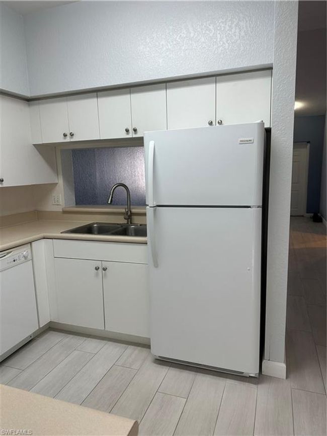 Kitchen featuring sink, white cabinetry, dishwashing machine, and white refrigerator | Image 7