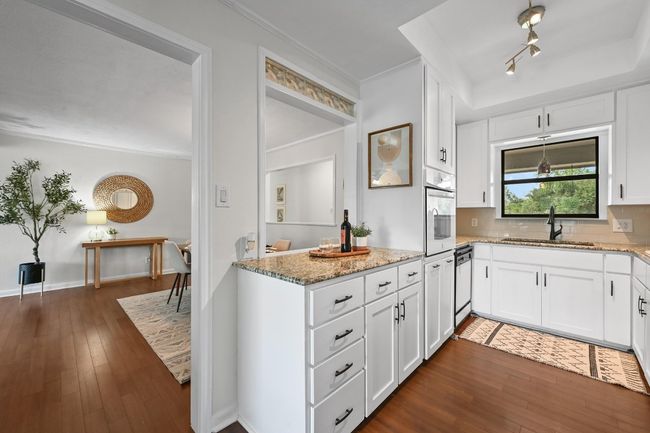 Kitchen featuring oven, a sink, light stone counters, white cabinets, and ornamental molding | Image 14
