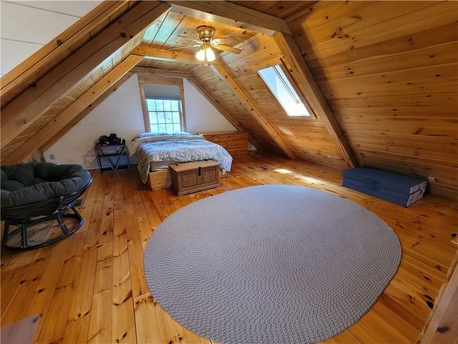 Bedroom featuring ceiling fan, vaulted ceiling with skylight, wood ceiling, and wood-type flooring | Image 7
