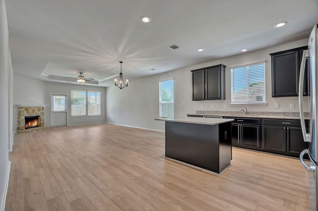 Kitchen featuring open floor plan, healthy amount of natural light, a center island, a stone fireplace, and recessed lighting | Image 7