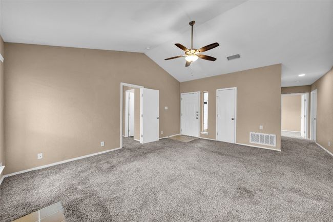 Unfurnished living room featuring vaulted ceiling, visible vents, carpet, and a ceiling fan | Image 9