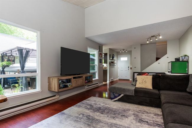 Living room with a baseboard heating unit and wood finished floors | Image 8