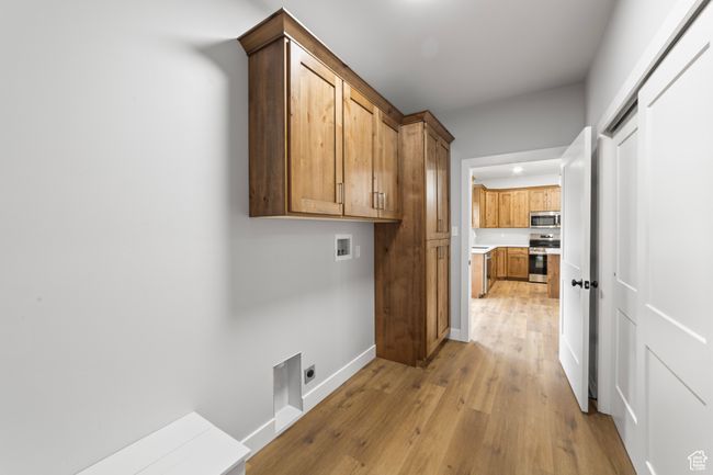 Clothes washing area featuring baseboards, cabinet space, light wood finished floors, electric dryer hookup, and washer hookup | Image 19