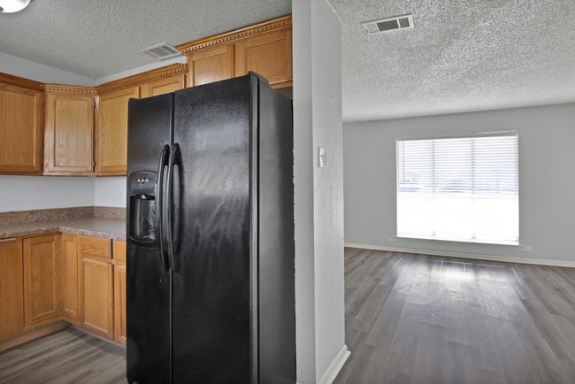 Kitchen featuring visible vents, black fridge, a textured ceiling, wood finished floors, and baseboards | Image 9