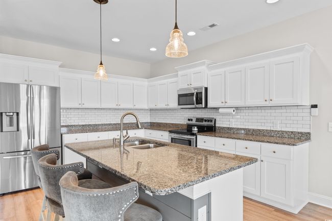 Kitchen featuring appliances with stainless steel finishes, white cabinetry, light wood-type flooring, and recessed lighting | Image 11