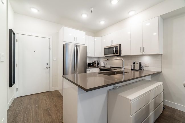 Kitchen with tasteful backsplash, a sink, a peninsula, appliances with stainless steel finishes, and dark wood-type flooring | Image 13