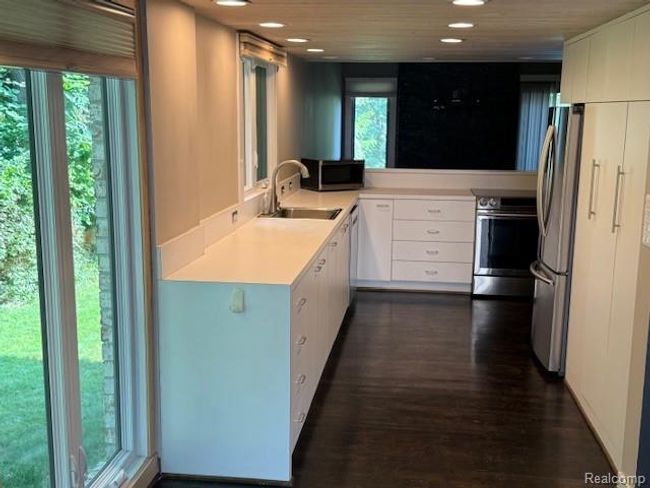 Kitchen featuring light countertops, appliances with stainless steel finishes, white cabinets, dark wood-style floors, and recessed lighting | Image 5
