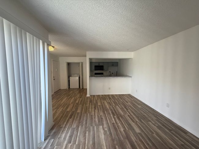 Unfurnished living room featuring dark wood-style flooring, a textured ceiling, and washer / dryer | Image 17