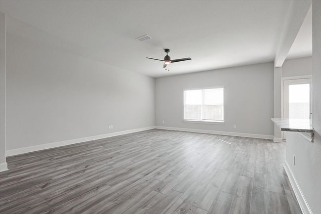 Empty room with baseboards, a ceiling fan, wood finished floors, and visible vents | Image 6