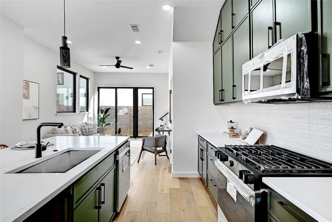 Kitchen with sink, range with gas cooktop, hanging light fixtures, and green cabinets | Image 10