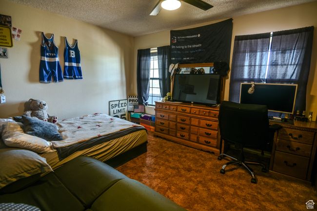 Carpeted bedroom with a textured ceiling, ceiling fan, and a desk | Image 37