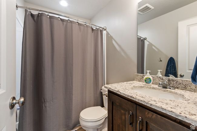 Full bath featuring a shower with shower curtain, visible vents, vanity, and toilet | Image 16
