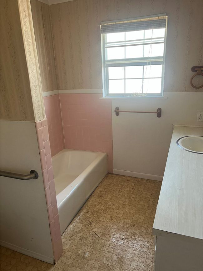 Bathroom featuring tile patterned floors, wallpapered walls, vanity, and a washtub | Image 9