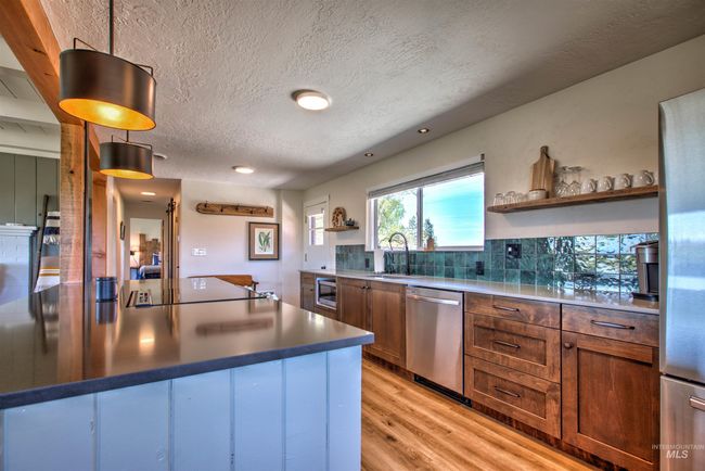 Kitchen with dishwasher, open shelves, black electric stovetop, light wood-style floors, and a textured ceiling | Image 11