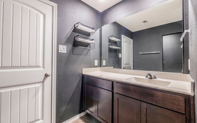 Bathroom with a textured wall and vanity | Image 12