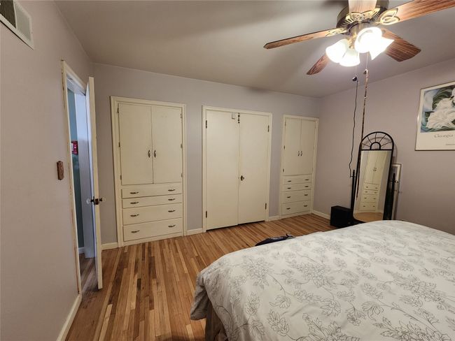 Bedroom with baseboards, multiple closets, visible vents, and light wood finished floors | Image 24