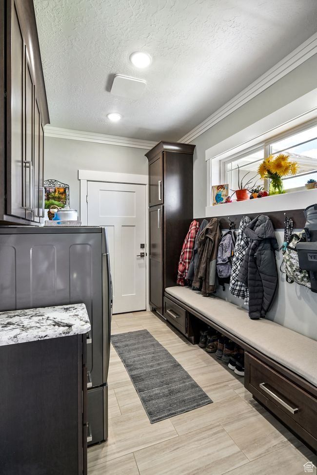 Mudroom featuring ornamental molding, washing machine and clothes dryer, and a textured ceiling | Image 34