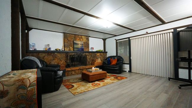 Living area with a fireplace and wood finished floors | Image 15