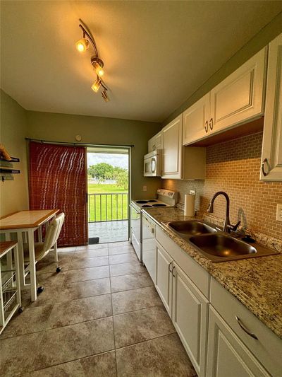 Kitchen has ample cabinet space, under counter lighting & sliding doors to rear patio. | Image 3