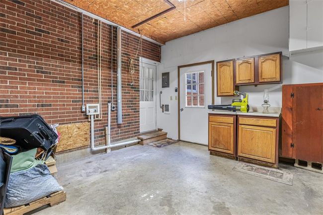 Kitchen featuring concrete flooring, brick wall, light countertops, an ornate ceiling, and electric panel | Image 61