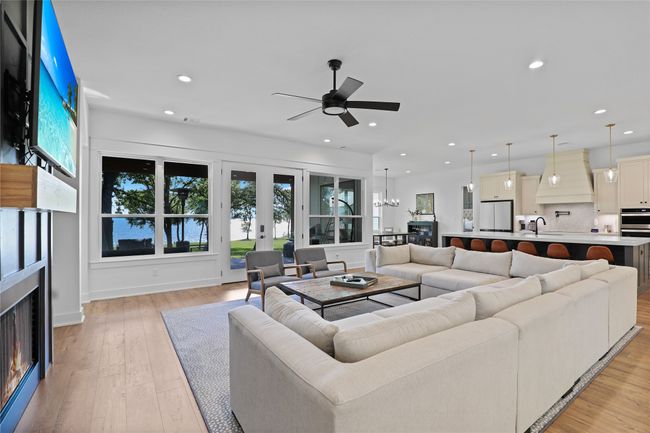 Living room with recessed lighting, a warm lit fireplace, light wood-type flooring, and ceiling fan with notable chandelier | Image 9