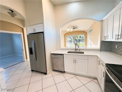 Kitchen with sink, white cabinets, stainless steel appliances, and light tile patterned floors | Image 2