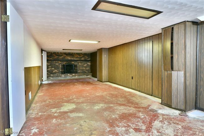 Unfurnished living room with a fireplace, wooden walls, concrete floors, and a textured ceiling | Image 37