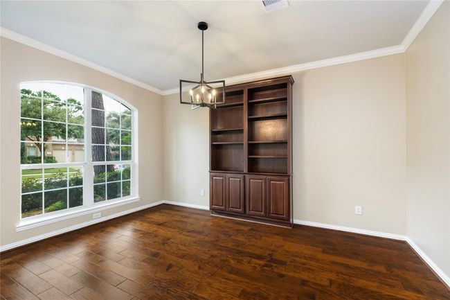 Ideal for a study, library, or quiet retreat, this versatile area includes a tall built-in bookcase, a huge front-facing window, and warm hardwood floors. | Image 9