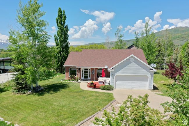 Single story home featuring an attached garage, driveway, a front yard, and a mountain view | Image 25