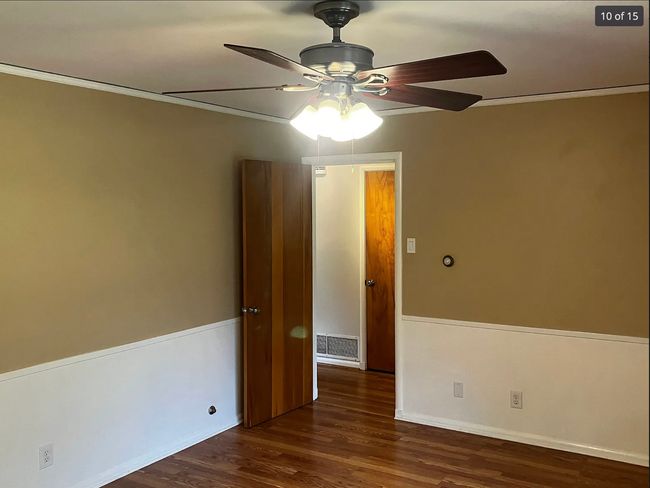 Spare room with dark wood finished floors, crown molding, and a ceiling fan | Image 9
