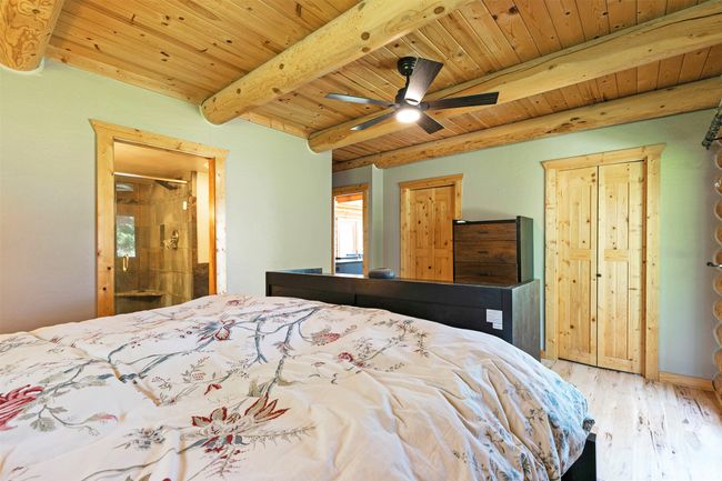 Master Bedroom with wooden ceiling with exposed beams, light wood finished floors, and connected bathroom | Image 21