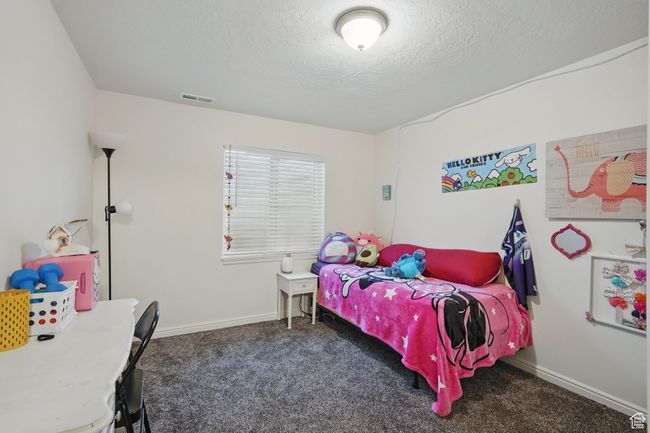 Carpeted bedroom featuring a textured ceiling, baseboards, and visible vents | Image 39