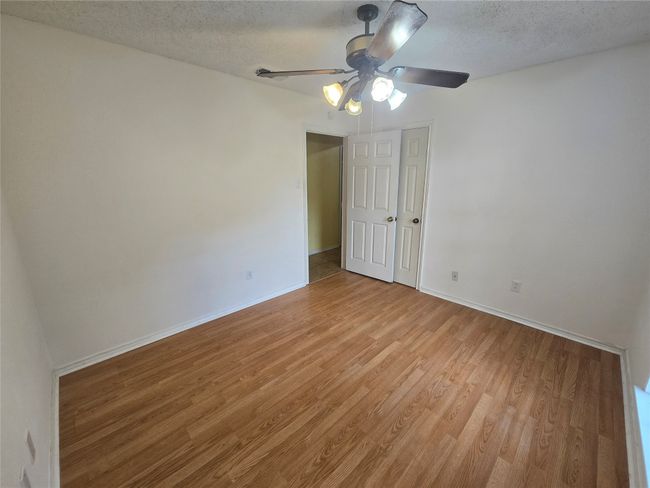 Empty room featuring light wood-type flooring, ceiling fan, and a textured ceiling | Image 17
