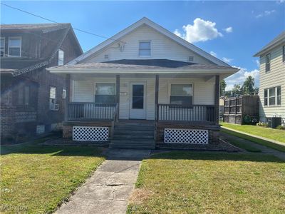 Bungalow featuring covered porch, cooling unit, and a front yard | Image 1