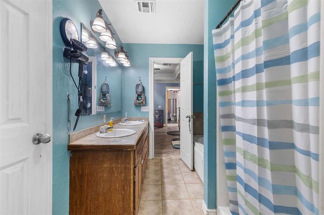 Bathroom with tile patterned flooring, vanity, and curtained shower | Image 17