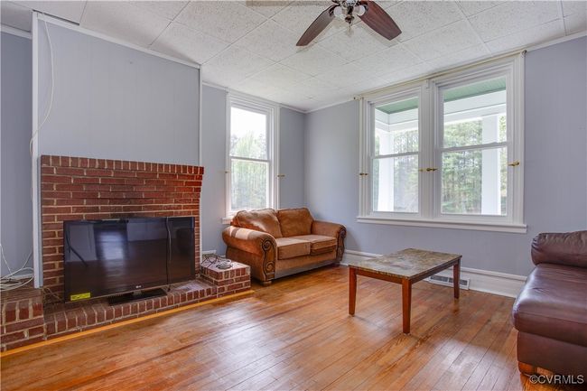 Living area featuring wood floors; a ceiling fan, visible vents, and ornate columns | Image 4