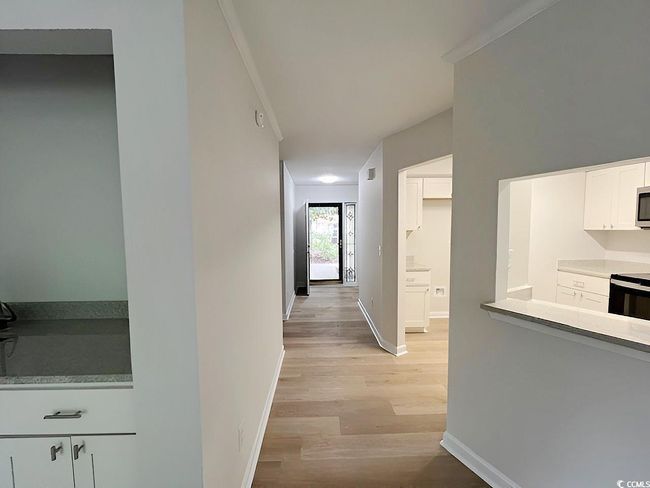 Hallway with baseboards, crown molding, visible vents, and light wood-type flooring | Image 39