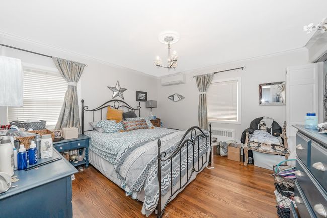 Bedroom featuring a wall unit AC, crown molding, a chandelier, and wood finished floors | Image 17