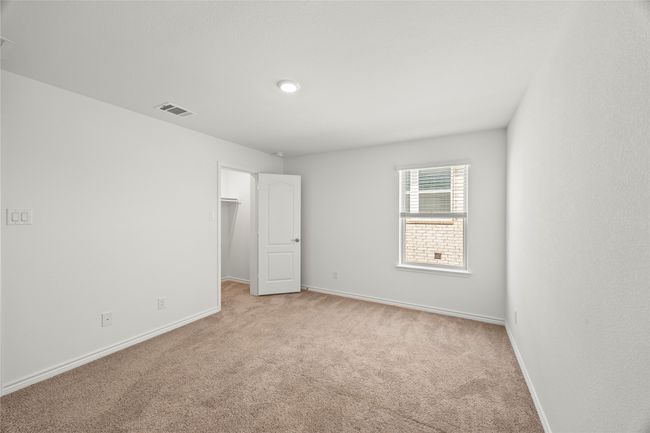 Unfurnished bedroom featuring light colored carpet, baseboards, and a walk in closet | Image 32