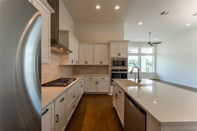 Kitchen with appliances with stainless steel finishes, wall chimney exhaust hood, recessed lighting, tasteful backsplash, and a ceiling fan | Image 16