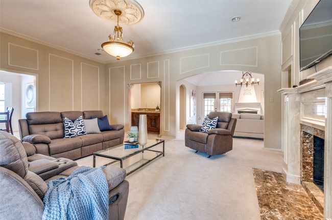 Living room featuring arched walkways, a decorative wall, light carpet, a fireplace, and ornamental molding | Image 10