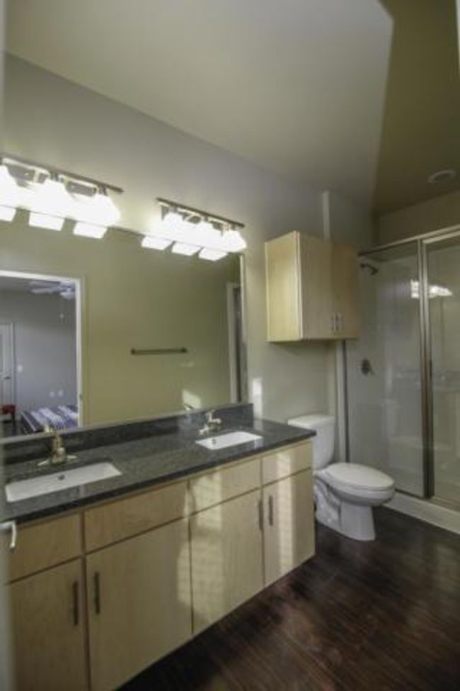 Full bath featuring a shower stall, double vanity, and wood finished floors | Image 4