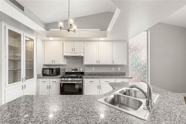 Kitchen featuring a sink, black microwave, gas range, under cabinet range hood, and visible vents | Image 9
