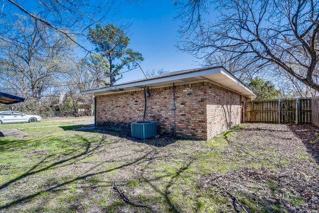 View of side of home featuring central AC unit, fence, brick siding, and a lawn | Image 17