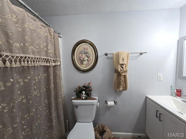 Full bathroom with vanity, a textured ceiling, and curtained shower | Image 18