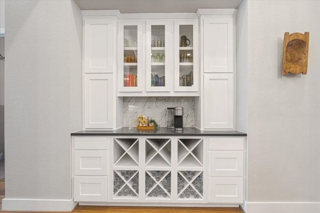 Indoor dry bar featuring tasteful backsplash, baseboards, wood finished floors, and a textured wall | Image 12