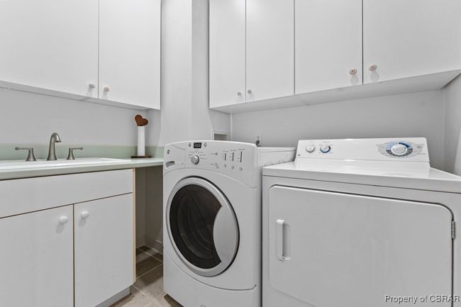 Laundry room with cabinet space, washing machine and dryer, and light tile patterned floors | Image 40
