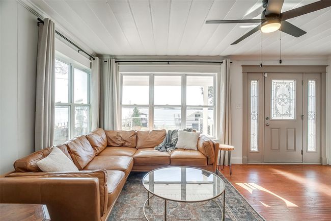 Living room with wood finished floors, ceiling fan, and crown molding | Image 10
